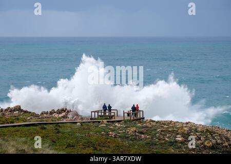 Carrapateira, Algarve, Portugal - Touristen auf einer Aussichtsplattform bestaunen die brüllende Brandung und den Sprühnebel nicht weit von Praia do Bordeira auf einem stürmischen Sprungbrett Stockfoto