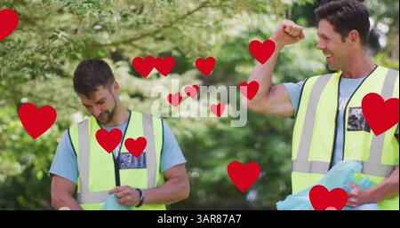 Bild von roten Herzen über die Feier der kaukasischen Gruppe, die Müll auf dem Land aufsammelt Stockfoto
