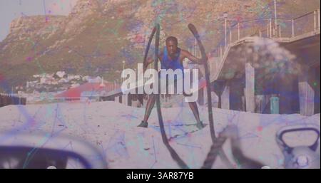 Netzwerk von Verbindungen gegen afroamerikanische Fitnessmänner, die am Strand Übungen mit einem Seil durchführen Stockfoto