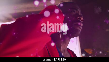 Leuchtende Molekülstrukturen, die gegen afroamerikanische Boxer schweben, die Ohrhörer tragen Stockfoto