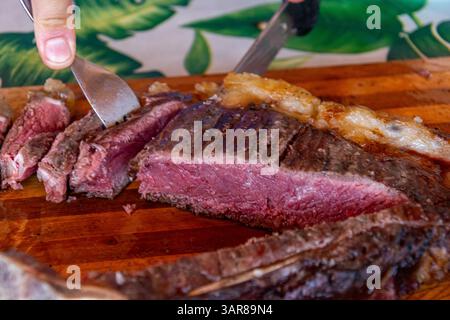 Köstliches Rindersteak in Scheiben auf einem Schneidebrett saftige Scheiben gegrilltes T-Bone Steak zum Servieren Stockfoto