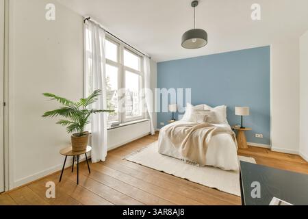 Ein gut beleuchtetes, modernes Wohnzimmer mit gemütlicher Couch, Topfpflanzen und warmem Holzboden. Das Dekor verbindet Komfort und Stil nahtlos. Stockfoto