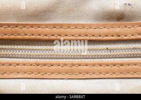 Reißverschluss an alter schmutziger weißer Kosmetiktasche mit braunen Ledereinsätzen, Reißverschluss Stockfoto