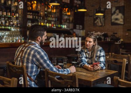 Barkeeper, ein Kellner und eine Kellnerin, sitzen vor der Eröffnung einer Cafeteria oder eines Konzeptrestaurants vor Beginn der Geschäftszeiten allein an der Bar, Stockfoto