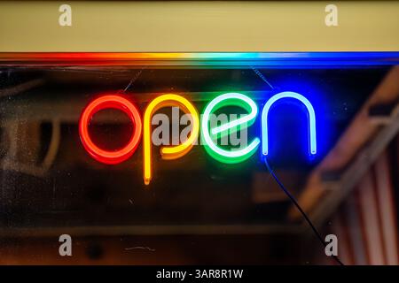 Offenes Zeichen für ein Geschäft. Leuchtende Neonlichtfarben an der Eingangstür eines Gebäudes. Nahaufnahme der farbenfrohen Schilder in einem Restaurant. Stockfoto