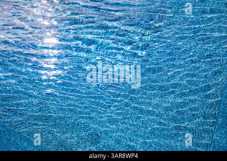 Blick aus der Nähe auf das abstrakte Schwimmbadwasser mit rauschendem Sommerlicht, perfekt für Design-Hintergründe, erfrischende Vibes und kreative tropische Inspiration Stockfoto