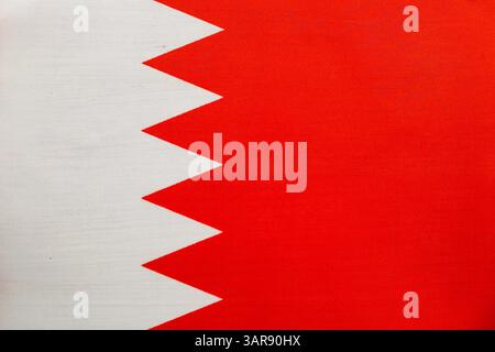 Die bahrainische Nationalflagge zeigt ein rotes Feld mit einem weißen gezackten Band, das vor einem hellblauen Hintergrund sichtbar ist und die Nationalflagge symbolisiert Stockfoto