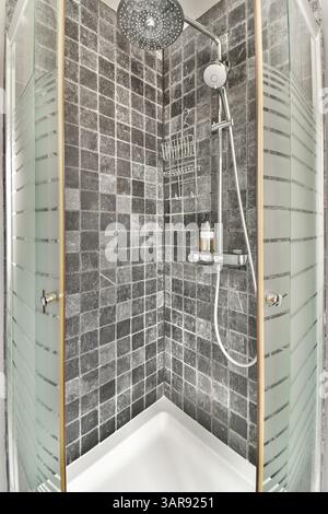 Eine stilvolle, moderne Duschkabine mit elegantem Fliesendesign und modernen Armaturen, perfekt für ein luxuriöses Badezimmer. Stockfoto