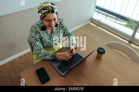 Hochwinkelansicht einer professionellen Frau, die in einem privaten Büro arbeitet. Sie ist an einem Meeting auf ihrem Laptop beteiligt und strahlt Selbstvertrauen und Konzentration aus. Die Stockfoto