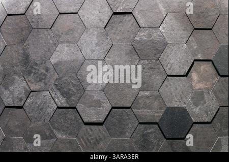 Dunkelgraue sechseckige Fliesen bilden einen strukturierten Hintergrund, ideal für Architektur- und Designprojekte Stockfoto
