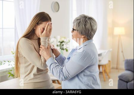 Eine ältere Frau beruhigt ihre verärgerte Erwachsene Tochter, die Probleme hat Stockfoto