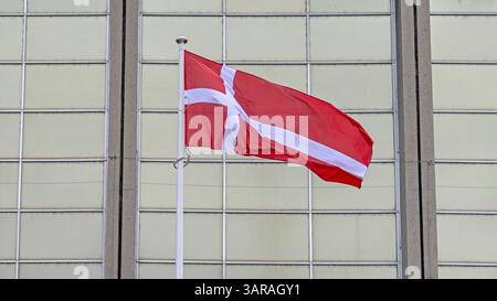 Älteste Flagge des Weltreichs Dänemark vor dem Glasgebäude Stockfoto