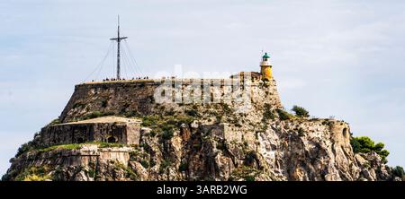 Eine historische Festung auf einer felsigen Klippe mit einem Leuchtturm und einem hohen Mast. Das Gebäude ist von Grün umgeben und bietet einen Panoramablick Stockfoto