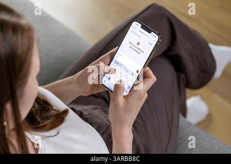 Posen, Polen – 14. April 2025: Eine Frau, die ein Smartphone hält und die Claude AI App nutzt, mit künstlicher Intelligenz über Texteingabe i kommuniziert Stockfoto