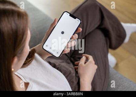 Posen, Polen – 14. April 2025: Eine Frau interagiert mit einer Assistentin der künstlichen Intelligenz auf ihrem Telefon über eine Spracheingabe mit Minimalist Stockfoto