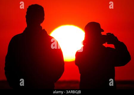 Isle Of Palms, Usa. April 2025. Ein Fotograf mit der Silhouette des Sonnenaufgangs macht Fotos, während die Sonne am Strand des Wild Dunes Resort am 17. April 2025 in Isle of Palms, South Carolina, aufgeht. Quelle: Richard Ellis/Richard Ellis/Alamy Live News Stockfoto