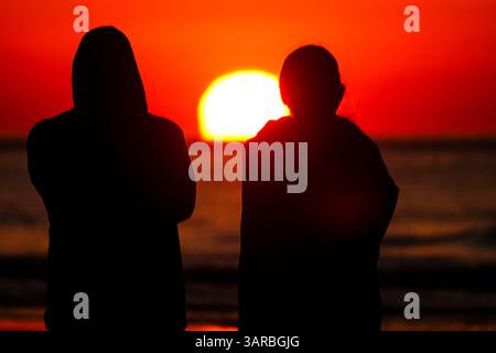 Isle Of Palms, Usa. April 2025. Ein Paar, das von der Sonnenaufgangsbeobachtung umgeben ist, während die Sonne vom Strand des Wild Dunes Resort am 17. April 2025 in Isle of Palms, South Carolina, über den Horizont steigt. Quelle: Richard Ellis/Richard Ellis/Alamy Live News Stockfoto