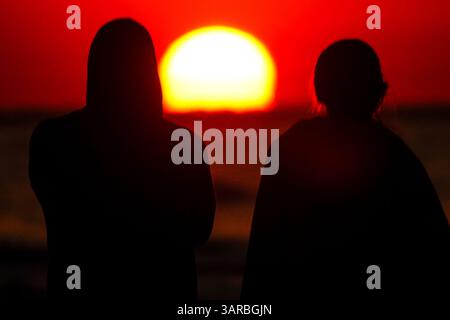 Isle Of Palms, Usa. April 2025. Ein Paar, das von der Sonnenaufgangsbeobachtung umgeben ist, während die Sonne vom Strand des Wild Dunes Resort am 17. April 2025 in Isle of Palms, South Carolina, über den Horizont steigt. Quelle: Richard Ellis/Richard Ellis/Alamy Live News Stockfoto