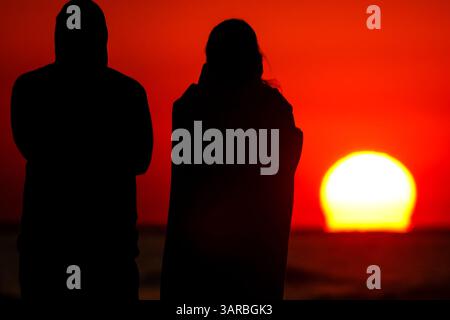 Isle Of Palms, Usa. April 2025. Ein Paar, das von der Sonnenaufgangsbeobachtung umgeben ist, während die Sonne vom Strand des Wild Dunes Resort am 17. April 2025 in Isle of Palms, South Carolina, über den Horizont steigt. Quelle: Richard Ellis/Richard Ellis/Alamy Live News Stockfoto