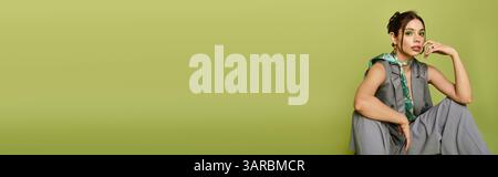 Eine stilvolle junge Frau sitzt anmutig und verbindet Kunst, Mode und einen Hauch von Farbe. Stockfoto