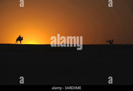 12. Mai 2010 – Kairo, Ägypten – ein Mann auf einem Kamel beobachtet den australischen Freestyle Moto Cross-Fahrer ROBBIE MADDISON beim Sonnenuntergang bei einem Training mit seinem Fahrrad in der Nähe der Pyramiden von Gizeh. Die zweite Etappe der Red Bull X-Fighters World Tour findet vor der Sphinx in Kairo statt. (Kreditbild: © Magnum PR /ZUMApress.com) Stockfoto