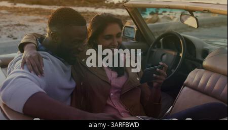 Bild eines glücklichen, vielfältigen Paares, das Selfie im Cabriolet macht Stockfoto