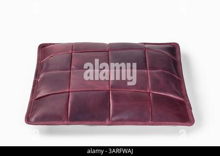 Burgunderfarbenes Lederkissen, das auf weißem Hintergrund schwebt: Moderne Inneneinrichtung Stockfoto
