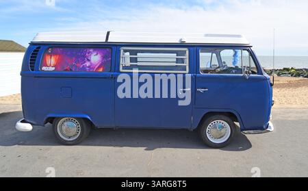 Klassischer Volkswagen Bus an der Strandpromenade Strand und Meer im Hintergrund. Stockfoto