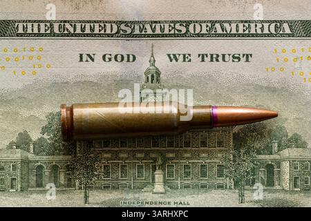 Die Kugel liegt auf einem Dollarschein, und der Text auf dem Gesetz steht in Gott, wir vertrauen, Geld für Waffen Stockfoto
