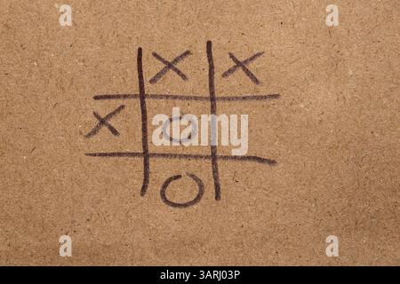 Kinderspiel Tic-Tac-Toe auf braunem Papier mit schwarzem Marker gezeichnet, Tic-Tac-Toe-Spiel Stockfoto