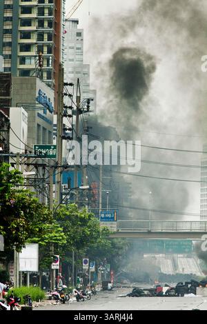 16. Mai 2010 - Bangkok, Thailand - Rauch steigt über der Skyline von Bangkok an brennenden Reifenbarrikaden entlang der Rama IV Road in der Nähe des Lumpini Boxstadions Sonntag. Thailändische Truppen und regierungsfeindliche Demonstranten stießen am Sonntagnachmittag erneut in einer Reihe von Schlachten auf der Rama IV Road zusammen. Truppen feuerten in die Luft und nicht identifizierte Scharfschützen schossen auf Fußgänger auf den Gehwegen. Irgendwann sagte die Regierung, sie werde eine Ausgangssperre verhängen, nur um die Ankündigung Stunden später aufzuheben. Die Lage in Bangkok verschlechtert sich weiter, da sich die Proteste über den Bereich der Red-Shirts-Bühne bei Ratte ausbreiteten Stockfoto