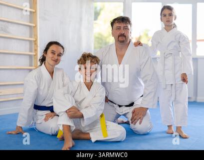 Freundliche, sportliche Familie mit zwei Kindern in Kimonos, die im Fitnessstudio posieren Stockfoto