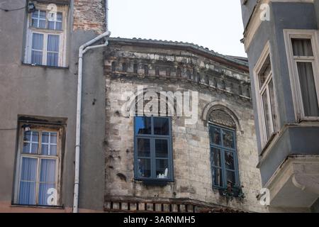 Altes Steingebäude mit Bogenfenstern in der engen städtischen Alley Stockfoto