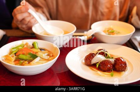 Frau isst ein Mittagsset gebratener Nudeln mit süß-saurem Schweinefleisch und Ankake Yakisoba (gebratene Nudeln mit stärkehaltiger Sauce) Stockfoto