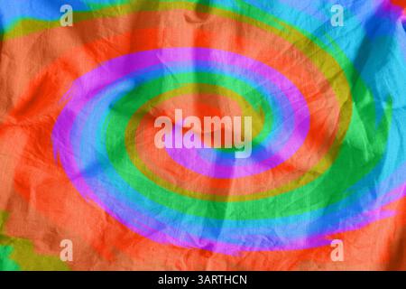 Helles, mit Tie-Dye-Technik gefärbtes Gewebe. Textil mit Wirbeln in Regenbogenfarben Stockfoto