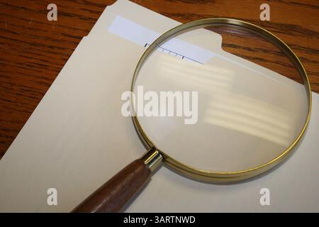 Eine Lupe und ein Aktenordner auf einem Schreibtisch. Stockfoto