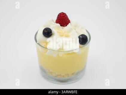 Vanillepudding mit Schlagsahne und frischen Beeren in einem Glas auf weißem Hintergrund Stockfoto