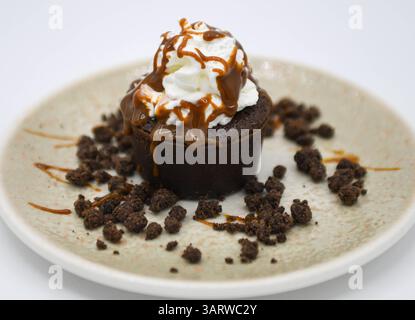 Schokoladenmuffin mit Schlagsahne und Schokoladenchips auf weißem Hintergrund Stockfoto