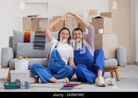 Junge schwangere Paare, die während der Reparatur im Zimmer Dachgesten machen Stockfoto