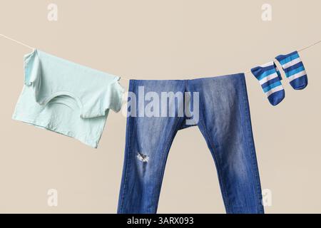 Sauberes T-Shirt, Hose und Socken, die an einem Seil an der Farbwand hängen Stockfoto