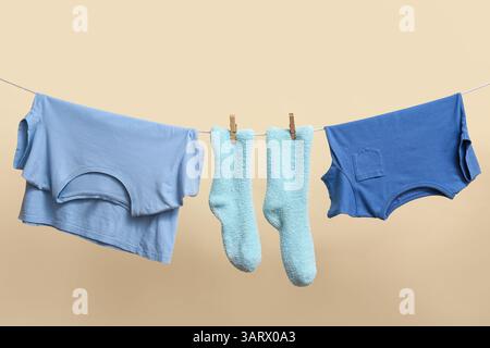 Saubere Socken und T-Shirts, die an einem Seil an der Farbwand hängen Stockfoto