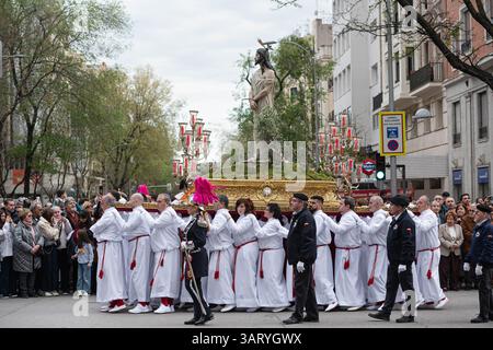Madrid, Spanien. April 2025. Costaleros tragen während einer feierlichen Osterprozession einen kunstvollen Wagen der Karwoche mit einer Statue Jesu Christi. Die Karwochenprozession in Madrid ist eine tief verwurzelte katholische Tradition, die in der Woche vor Ostern stattfindet. Mit feierlichen Paraden mit religiösen Wagen, traditioneller Musik und Teilnehmern in Bußgewändern spiegelt die Veranstaltung das reiche spirituelle Erbe Spaniens wider und zieht jedes Jahr Tausende von Zuschauern an. (Foto: Michele Parisato/SOPA Images/SIPA USA) Credit: SIPA USA/Alamy Live News Stockfoto