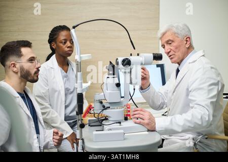 Oberarzt demonstrierte die Verwendung medizinischer Untersuchungsgeräte bei männlichen und schwarzen Ärzten in der Ausbildung in der modernen Klinik Stockfoto