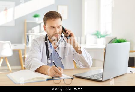 Männlicher ernsthafter Arzt, Mann, der mit dem Patienten im Büro spricht, Laptop am Arbeitsplatz benutzt Stockfoto