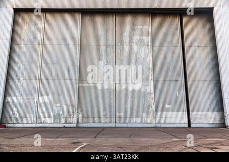 Die Fassade eines großen Metallhangars mit einem Tor. Stockfoto