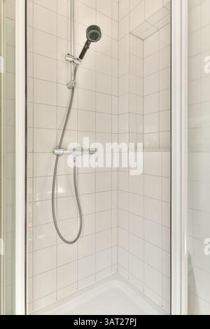 Eine elegante und minimalistische Duschkabine mit weiß gefliesten Wänden und einem modernen Handbrause, perfekt für moderne Badezimmer. Stockfoto