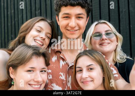 Fröhliche junge Freunde, die draußen nahe beieinander lächeln Stockfoto