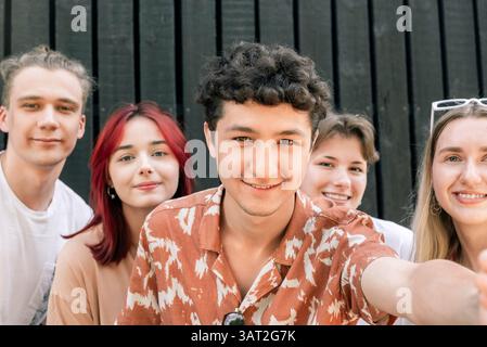 Junge Freunde lächeln, während sie draußen ein Selfie machen Stockfoto