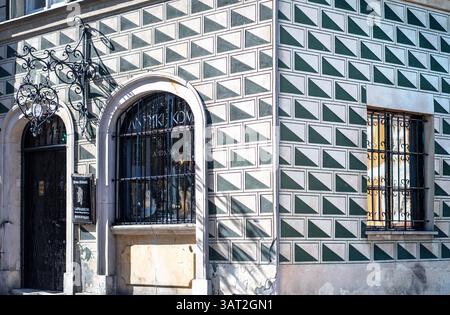 Ein Eckgebäude mit einer einzigartigen geometrischen Fassade mit grünen und weißen Rautenmustern. Der Eingang hat ein kunstvoll verziertes schmiedeeisernes Schild und ist verschlossen Stockfoto