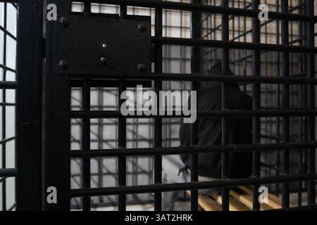 Ein Häftling mit Kapuze sitzt in einer geschlossenen, vorübergehenden Zelle. Stockfoto